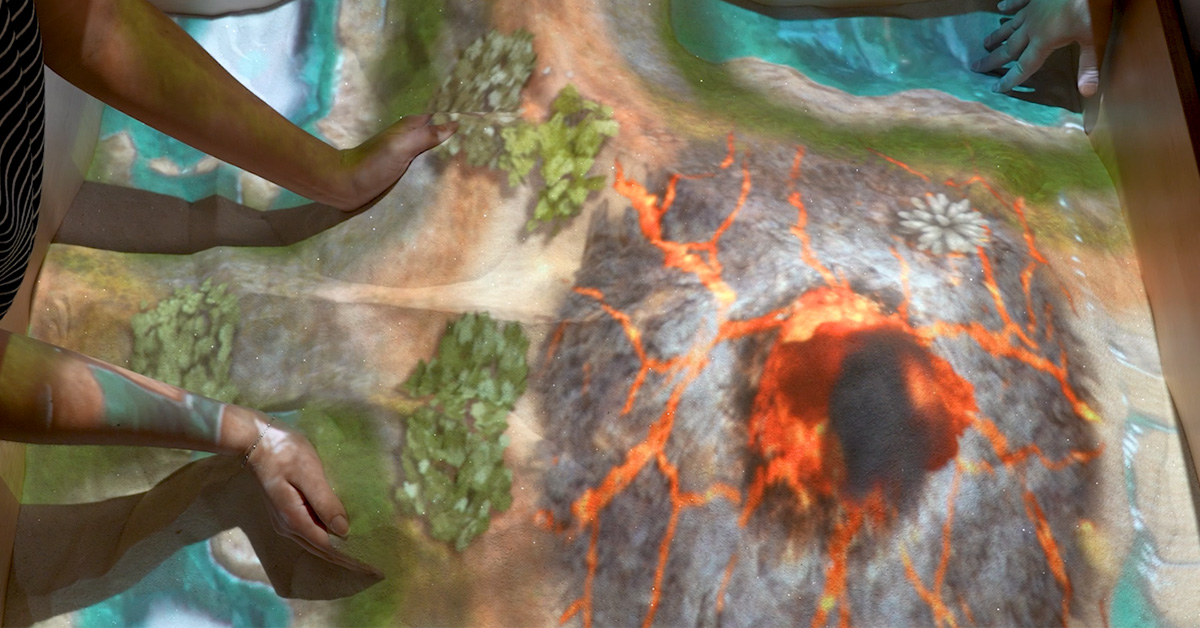 students engaging in immersive learning by forming volcanos and other landscapes using Diversified's augmented reality sandbox